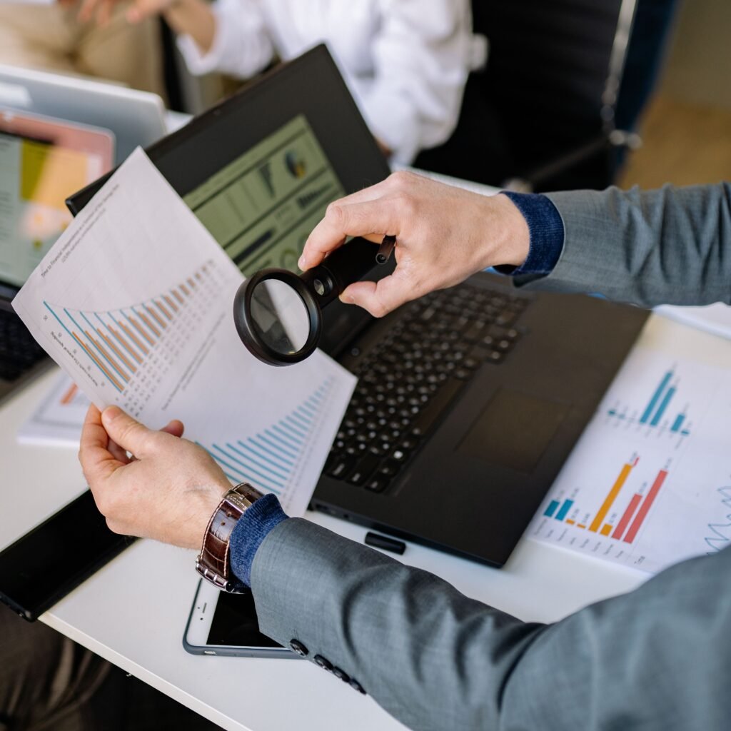 Person checking charts and figures with a magnifying glass to estimate costs