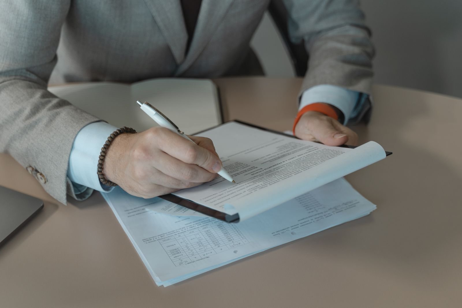 Person holding a pen and a document on a clipboard