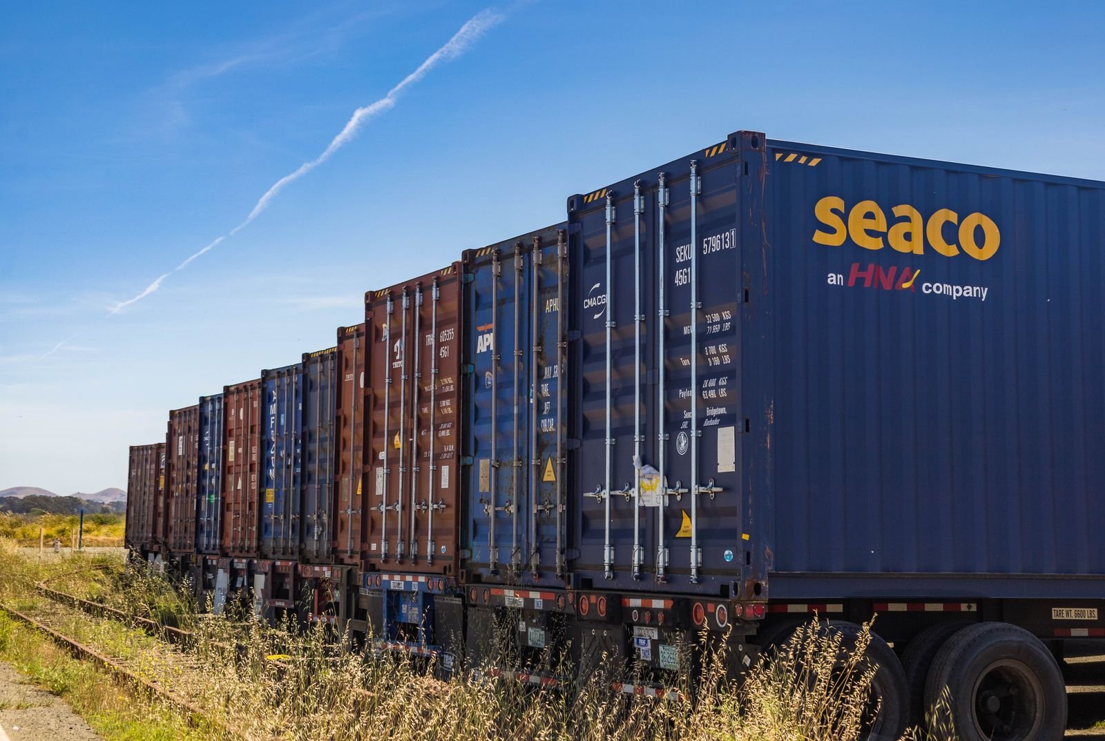 Cargo containers and trucks beside a railroad for inland transport