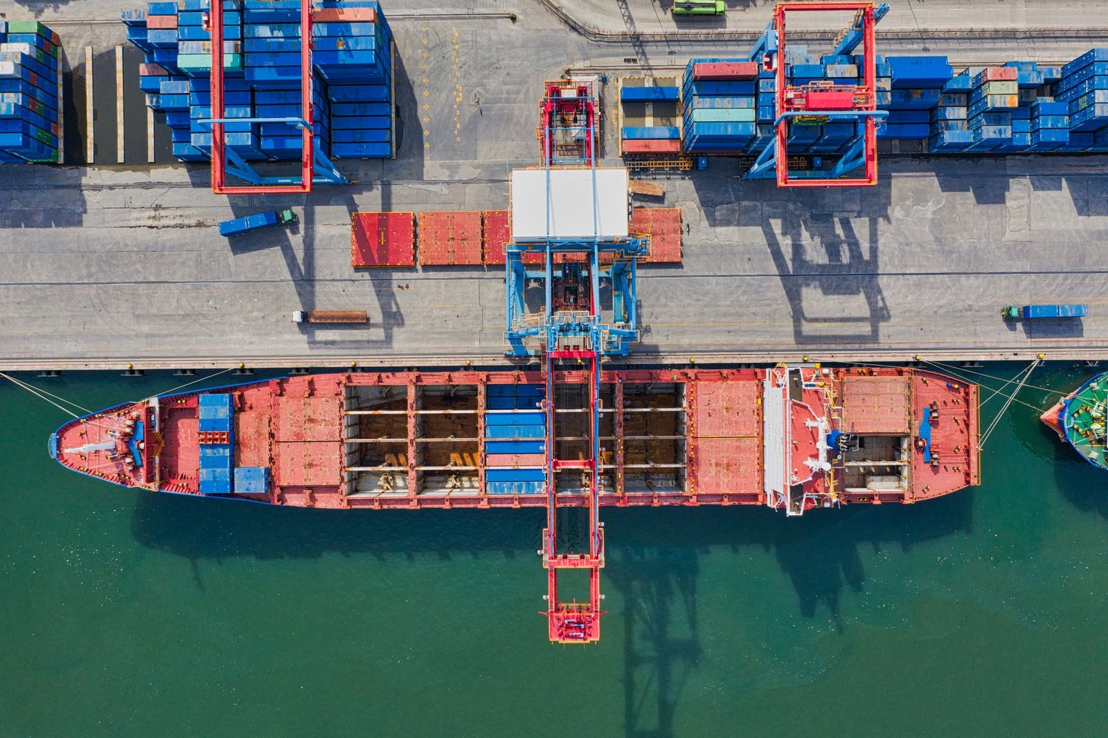 Aerial view of a cargo ship beside stacked intermodal containers
