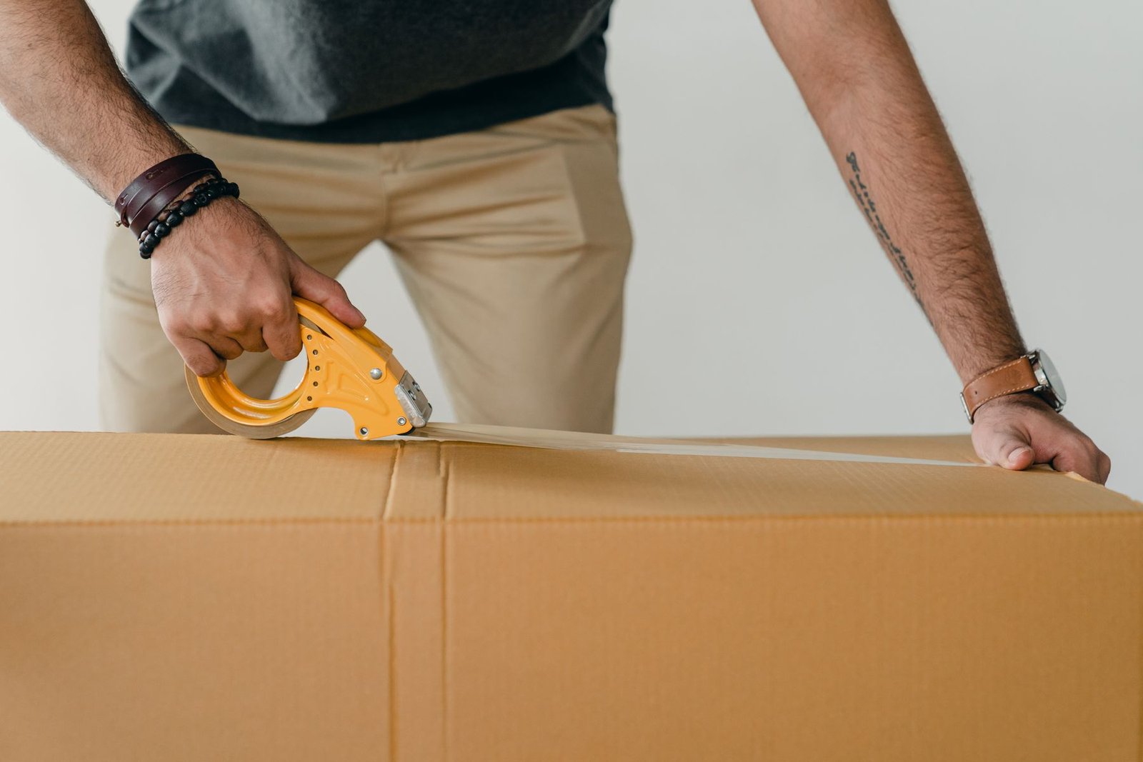 Man sealing a carton box with tape to prepare goods for LCL shipping