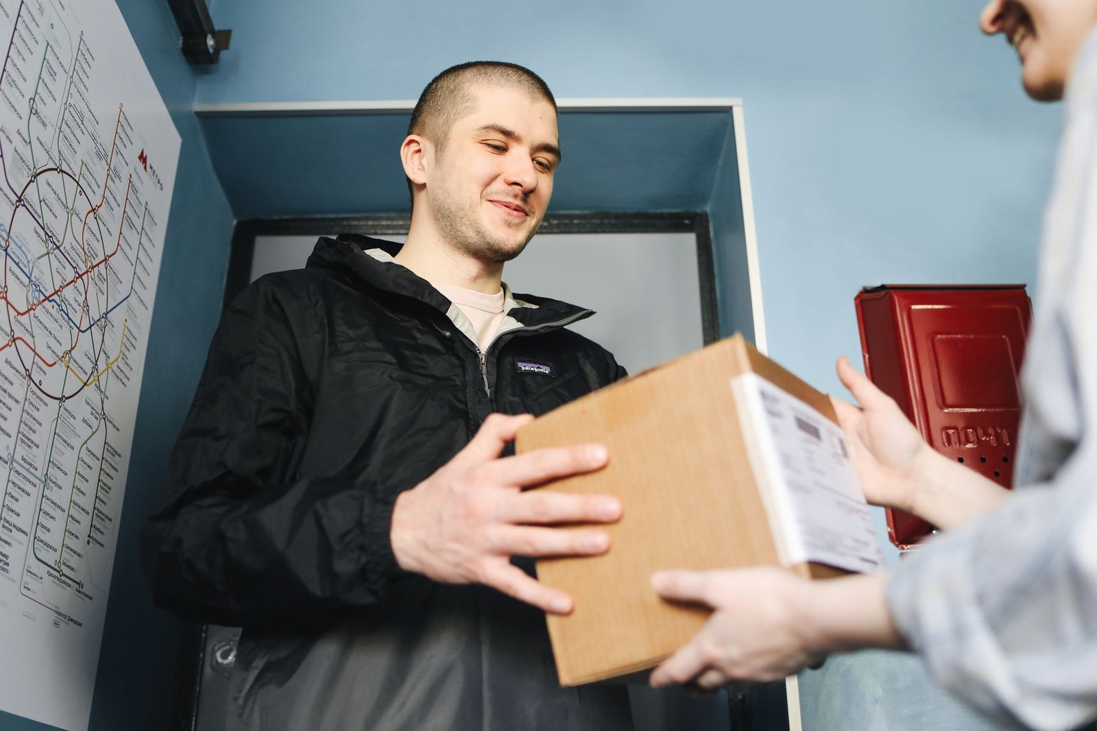 Delivery person handing over a cardboard box at the customer door