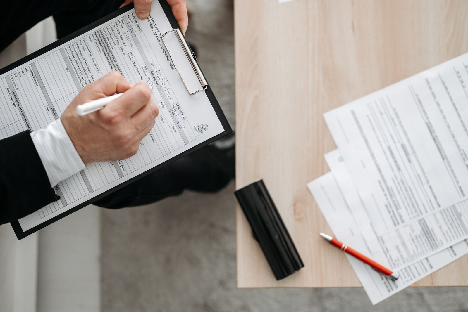 Person holding a clipboard and pen checking shipping documents